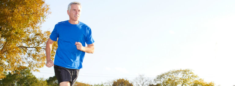 Senior man in blue athletic shirt running outside