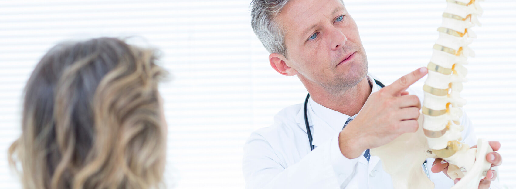 Male doctor reviewing a spine model with female patient