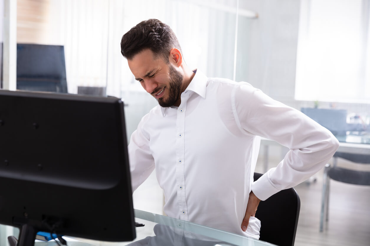 Employee sitting at his desk with back pain.