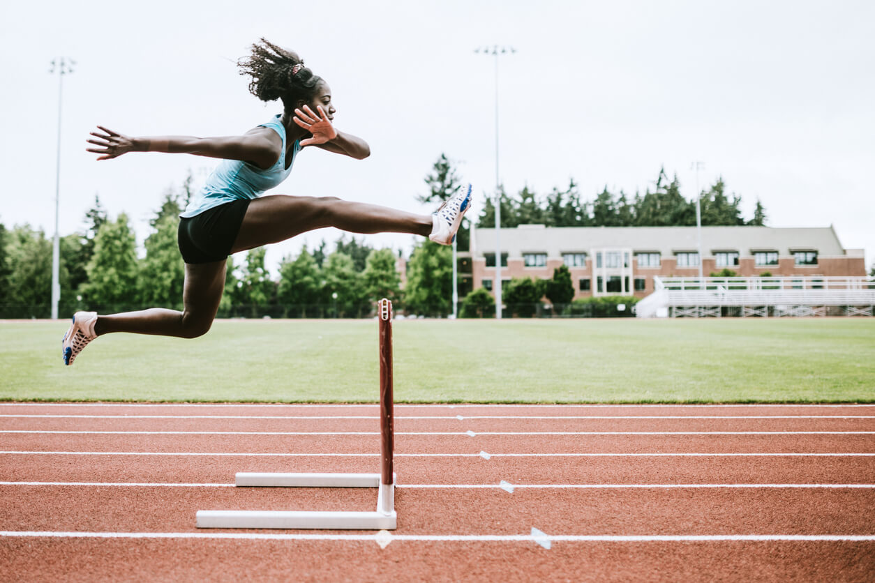 woman jumping over hurdles