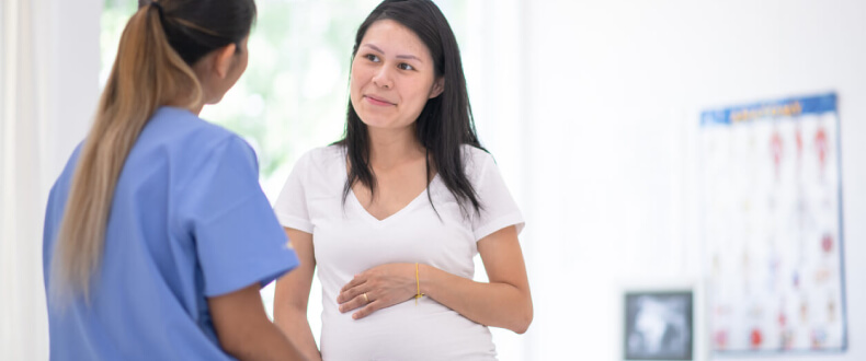 Pregnant woman speaking with female doctor