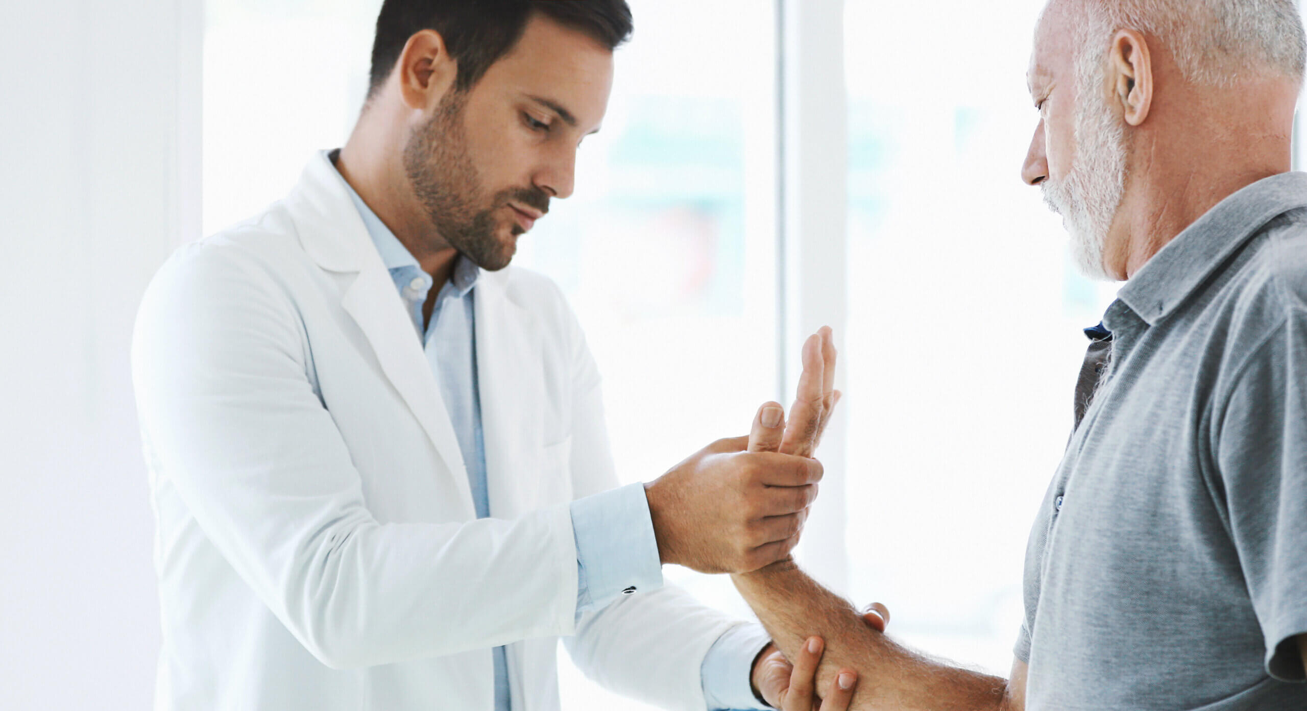 man checking elderly man's stiffness