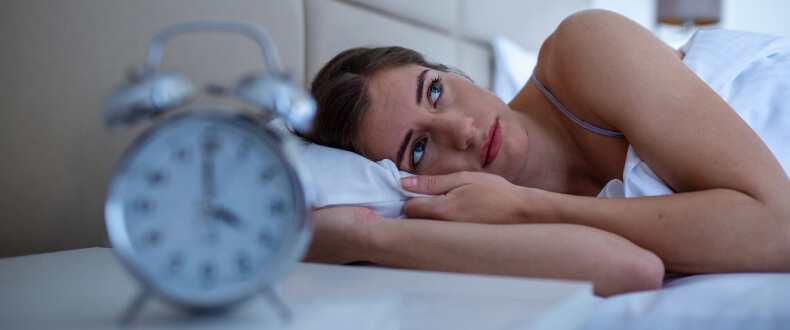 Young woman lying awake in bed with insomnia