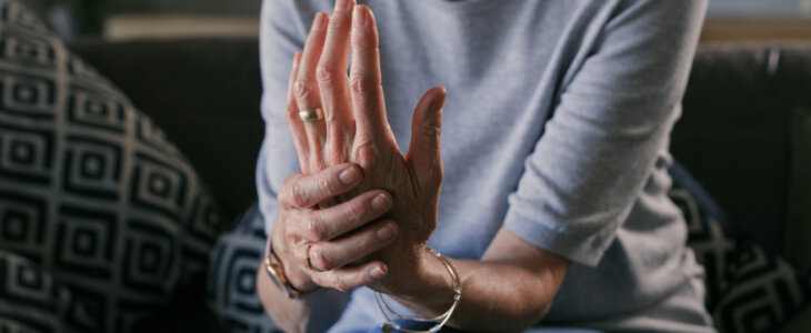 Woman holding her left hand due to arthritis pain