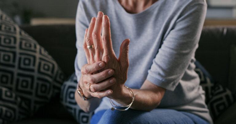 Woman holding her left hand due to arthritis pain