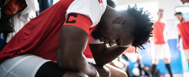 Soccer player with elbows on knees and hand on head