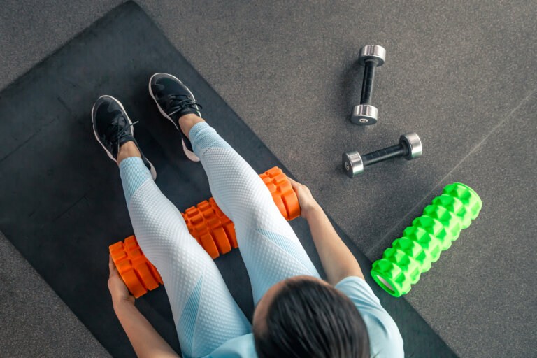 Overhead view of woman using foam roller and weights to prevent sports injuries
