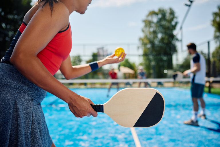 woman serving the ball while playing mixed doubles in pickleball