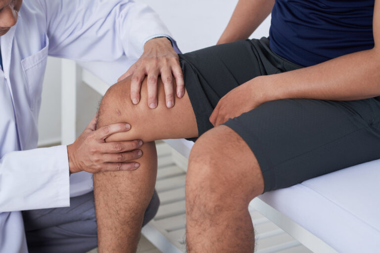 Doctor checking knee of male patient