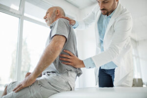 Closeup side view of a mature man having his spine examined at doctor's office.