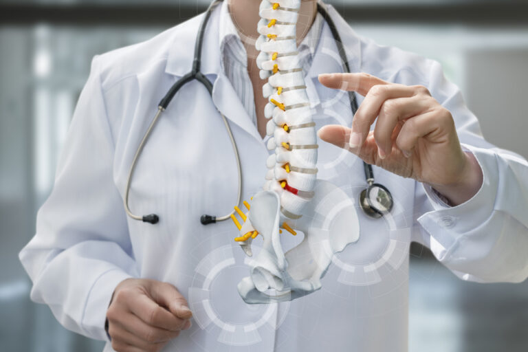 Medical professional wearing a white coat and stethoscope illustrates the spinal structure with 3D graphics in a contemporary healthcare setting. The focus is on vertebrae and disc positions.