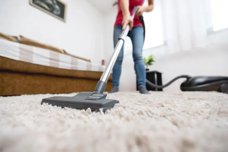 Woman vacuuming her room, hurting her spine