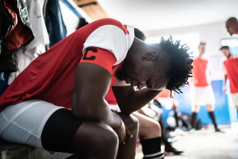 Soccer player with elbows on knees and hand on head