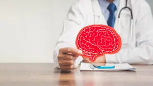 Midsection of a doctor in a uniform holding a brain symbol made from red paper